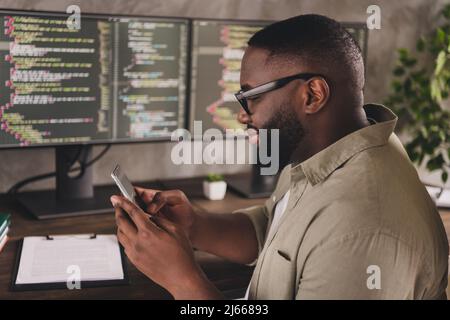 Profil Seitenansicht Porträt von gut aussehend fokussierten fröhlich qualifizierten Kerl mit Gerät Gadget App Blogging am Arbeitsplatz Arbeitsplatz in Innenräumen Stockfoto