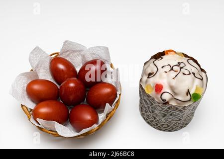Osterkuchen und ein bemaltes Ei liegen auf weißem Hintergrund. Hochwertige Fotos Stockfoto