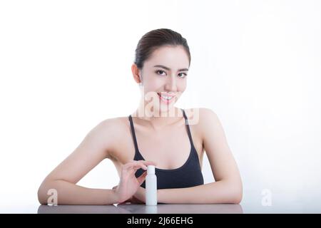 Schöne junge chinesische Frau zeigt Körperpflegeprodukte, auf weißem Hintergrund - Stock Foto Stockfoto