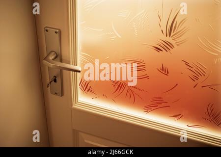 Verschlosene Glastuere in einem Wohnhaus mit Tuergriff und Tuerschluessel, Detail, Oberoesterreich, Oesterreich Stockfoto