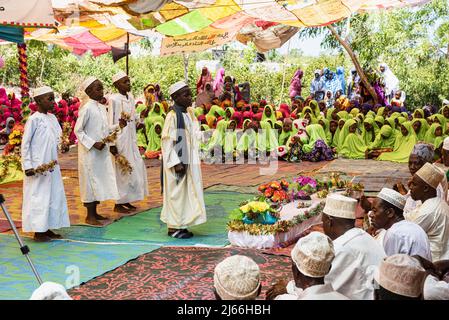 Jungen, Maenner und hinten Frauen bei muslimische Feier unter Zeltdach zum Geburtstag Mohammeds auf Tumgatu, Sansibar, Tansania Stockfoto