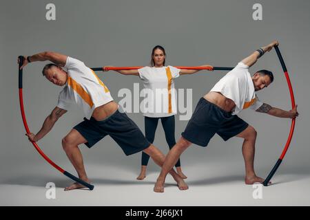 Menschen stehen zusammen und üben Stöcke. Karate-Meister posieren mit Stöcken im Studio zusammen. Stockfoto