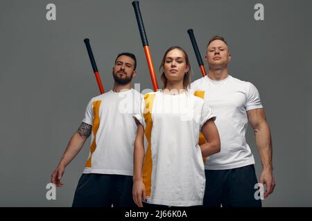 Menschen stehen zusammen und üben Stöcke. Karate-Meister posieren mit Stöcken im Studio zusammen. Stockfoto