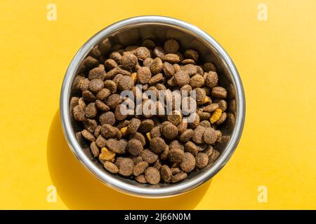 Kibble in PET-Schale auf dem gelben Hintergrund Stockfoto