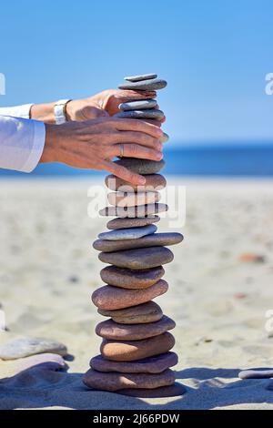 Frauenhände bauen eine hohe Kaira an einem Sandstrand Stockfoto