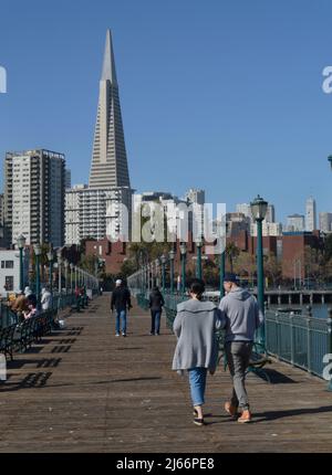 Touristen genießen den beliebten Pier 7 Angelpier mit seiner Fernsicht auf das Wahrzeichen Transamerica Pyramid Gebäude und die Skyline von San Francisco. Stockfoto