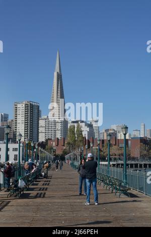 Touristen genießen den beliebten Pier 7 Angelpier mit seiner Fernsicht auf das Wahrzeichen Transamerica Pyramid Gebäude und die Skyline von San Francisco. Stockfoto