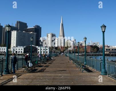 Touristen genießen den beliebten Pier 7 Angelpier mit seiner Fernsicht auf das Wahrzeichen Transamerica Pyramid Gebäude und die Skyline von San Francisco. Stockfoto