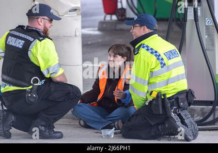 Kent, Großbritannien. 28. April 2022 Demonstranten von Just Stop Oil blockieren die BP-Garage bei Clacket Lane Services am M25. Die Polizei kommt, um alle Demonstranten zu entkleben und zu verhaften. Kredit: Denise Laura Baker/Alamy Live Nachrichten Stockfoto