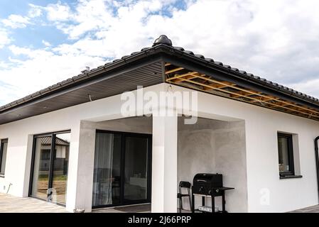 Gerüst mit drei Reihen von Holzlatten und einem modernen Graphitsoffit aus halbierten, sichtbaren H- und J-Lamellen. Stockfoto