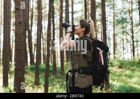 Wanderer, der mit einer modernen spiegellosen Kamera im grünen Wald fotografiert Stockfoto