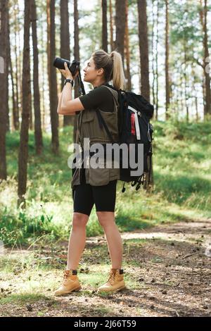 Wanderer, der mit einer modernen spiegellosen Kamera im grünen Wald fotografiert Stockfoto