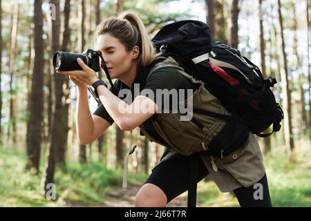 Wanderer, der mit einer modernen spiegellosen Kamera im grünen Wald fotografiert Stockfoto