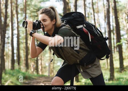 Wanderer, der mit einer modernen spiegellosen Kamera im grünen Wald fotografiert Stockfoto