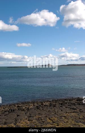 Porträtaufnahme von Low Newton mit Blick über die Bucht zu einer weit entfernten Burg von Dunstanburgh Stockfoto