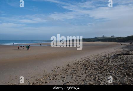 Breiter, weitläufige Strand der Embleton Bay mit Ebbe und einem fernen Dunstanburgh Castle am Horizont an einem Herbstnachmittag Stockfoto