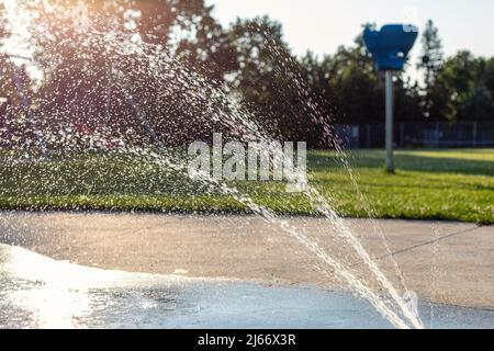 Spielplatz im öffentlichen Park im Sommer ohne Menschen. Brunnen mit spritzendem Wasser an einem sonnigen Tag. Stockfoto