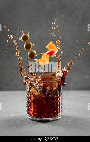 Wermouth Cocktail spritzt aus Glas auf hellgrauem Hintergrund. Vertikales Format. Stockfoto
