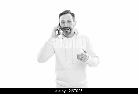 Lächelnder, hübscher, reifer Mann im Kapuzenpulli, der isoliert auf Weiß telefoniert, spricht. Stockfoto