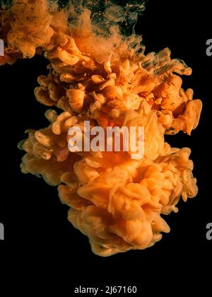 Orangefarbene Acrylfarbe in Wasser auf Schwarz. Stockfoto