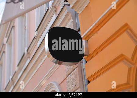 Kleines abgerundetes schwarzes Schild an der Fassade des Gebäudes in der Hauptstraße. Leer für Werbeaktion mit Firmenlogo Stockfoto
