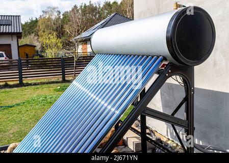 Ein moderner Solardruckkollektor, um heisses Warmwasser zu erhitzen, steht vor dem Haus auf dem Rasen. Stockfoto