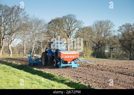 Nahaufnahme eines Traktors mit angefügter Saatbohrung und Düngemittelapplikator zur Aussaat von Mais in einem neuen Mist-vorbereiteten Maisfeld bei Oldend in Anderen Stockfoto