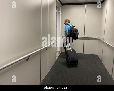 Orlando, FL USA - 23. September 2021: Ein Mann, der auf dem jetway läuft, um an einem Flughafen ein Flugzeug zu besteigen. Stockfoto