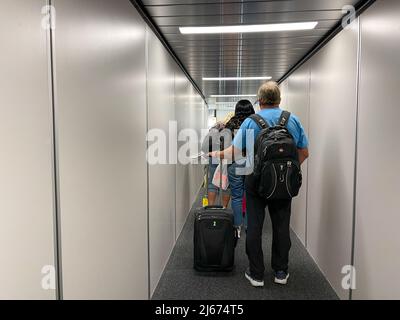 Orlando, FL USA - 23. September 2021: Ein Mann, der auf dem jetway läuft, um an einem Flughafen ein Flugzeug zu besteigen. Stockfoto