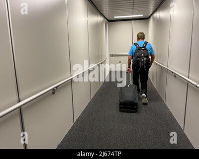 Orlando, FL USA - 23. September 2021: Ein Mann, der auf dem jetway läuft, um an einem Flughafen ein Flugzeug zu besteigen. Stockfoto