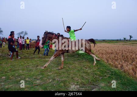 Ein junger Jockey reitet auf einem Pferd während eines Rural Horse Race. Nach der Erntezeit werden jedes Jahr in diesen Feldern Pferderennen veranstaltet. Die Jockeys, die Kinder sind, reiten Pferde ohne jegliche Schutz- oder Sicherheitsausrüstung. Stockfoto