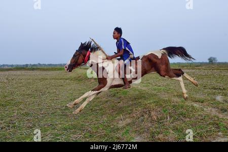 Parganas, Indien . 28. April 2022. 28. April 2022, South 24 Parganas, Westbengalen, Indien: Ein junger Jockey reitet auf einem Pferd während eines Rural Horse Race. Nach der Erntezeit werden jedes Jahr in diesen Feldern Pferderennen veranstaltet. Die Jockeys, die Kinder sind, reiten Pferde ohne jegliche Schutz- oder Sicherheitsausrüstung. (Bild: © Sumit Sanyal/SOPA Images via ZUMA Press Wire) Bild: ZUMA Press, Inc./Alamy Live News Stockfoto