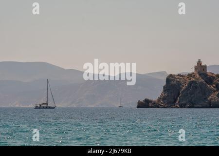 Blick auf ein Segelboot in der Ferne und einen Leuchtturm im Hintergrund auf der Insel iOS in Griechenland Stockfoto