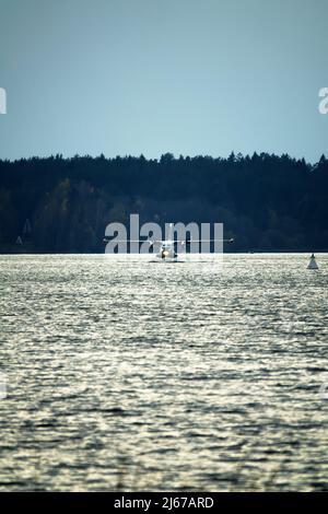 Das zweimotorige Wasserflugzeug ein Wasserflugzeug steigt aus dem Wasser, aus dem Waldsee, dem nördlichen Land auf. Wasserflugzeug Stockfoto