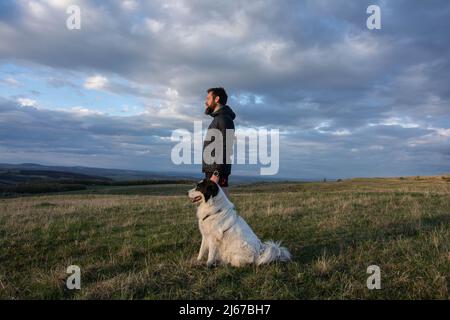 Bärtiger Mann, der die wunderschöne Landschaft mit seinem Hund genießt Stockfoto