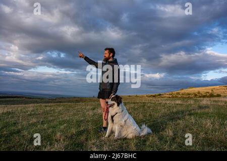 Bärtiger Mann, der die wunderschöne Landschaft mit seinem Hund genießt Stockfoto