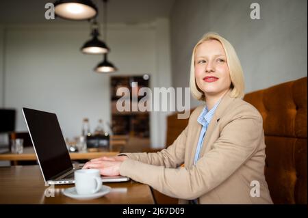 Schöne fröhliche Frau Freiberuflerin mit guter Laune mit Laptop Computer für Fernarbeiten beim Mittagessen in der Café-Bar, attraktive Frau mit schönen s Stockfoto