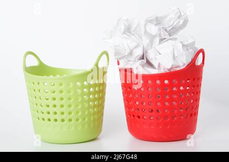 Zwei Körbe. Der grüne Korb ist leer - der rote ist voll. Leeren des Abfallkorbs. Dateien werden dauerhaft gelöscht. Zerknittertes Papier im Abfalleimer. Stockfoto