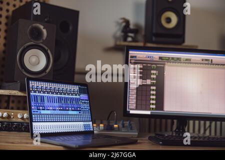 Nahaufnahme des eingeschalteten Laptops und des Monitorbildschirms auf dem Tisch im Rundfunk- und Aufnahmestudio Stockfoto