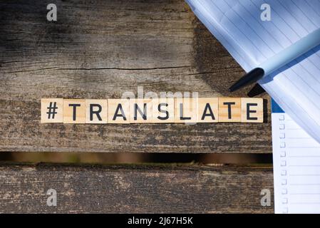 Holzspielzeugblöcke mit dem Text übersetzen mit Stift und Papier im Hintergrund Stockfoto