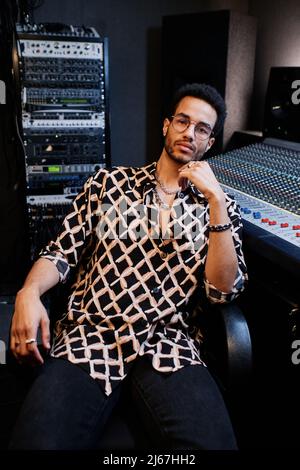 Porträt eines eleganten jungen schwarzen Mannes, der im Aufnahmestudio arbeitet und entspannt die Kamera anschaut Stockfoto