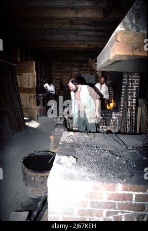 Williamsburg, VA. USA 9/1987. Meisterschmiede für Colonial Williamsburg. Diese Schmiede basteln die Metallbefestigungen, die von anderen Handwerkern aus Colonial Williamsburg verwendet werden, wie zum Beispiel den Radrecher, die Hausbefestigungen wie Nägel, Scharniere und Verriegelungen, und cooper-Eimer- und Laufbänder sowie landwirtschaftliche Ausrüstung und Reparatur. Stockfoto