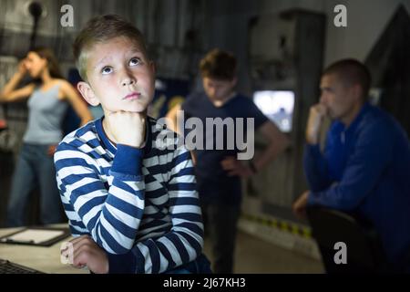 Nachdenklicher Teenager Junge, der Rätsel im Fluchtzimmer löst Stockfoto