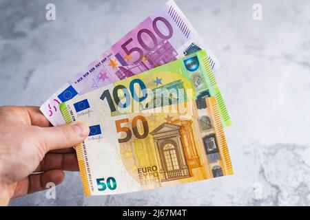 Hand mit fünfhundertfünfzig Euro-Banknoten. Geld in Menschenhand auf grauem Hintergrund Stockfoto