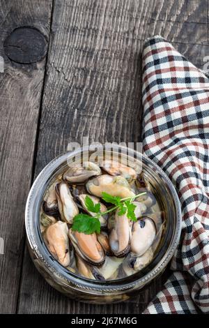 Marinierte Muscheln in einem Glas auf einem Holztisch Stockfoto