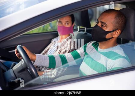 Mann und Frau in Masken im Auto Stockfoto