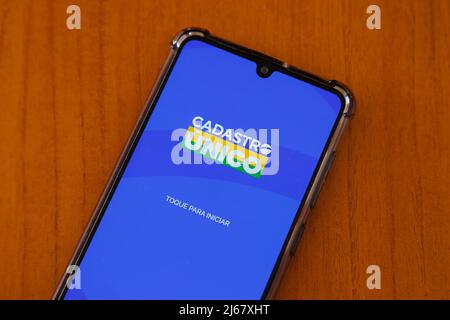 Minas Gerais, Brasilien - 24. April 2022: Detail von Cadastro Unico - CadUnico - Anwendungsbildschirm auf dem Smartphone mit Holzhintergrund Stockfoto