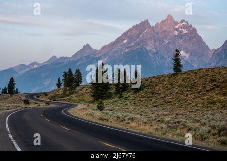 Winding Road klettert auf den Hügel vor der Teton Range Stockfoto