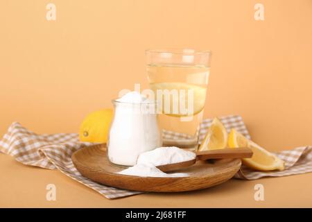 Teller mit Backpulver, Zitrone und Glas Wasser auf farbigem Hintergrund Stockfoto