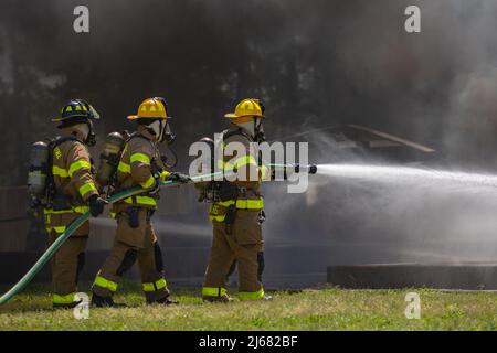 Jeremy Cain, links, Owen Fowler, Mitte, und Ethan Harris, Richtig, alle Feuerwehrmänner mit Camp Lejeune Fire and Emergency Services löschten ein simuliertes Flugzeugfeuer während eines Flughafenfeuerwehrs, der auf dem Marine Corps Base Camp Lejeune, North Carolina, am 9. April 2022 praktisch war. Alle Mitarbeiter des Camp Lejeune Fire and Emergency Services müssen eine Flughafenfeuerwehrzertifizierung erhalten, um jede Mission an Bord der Marine Corps Air Station New River zu unterstützen. (USA Marine Corps Foto von Lance CPL. Alexis Sanchez) Stockfoto